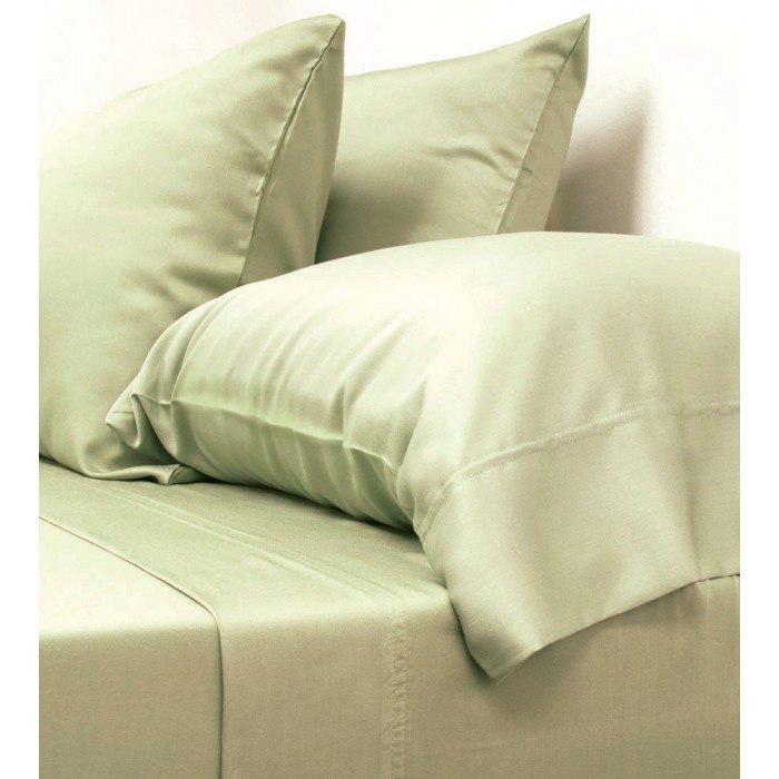 A neatly made bed with light sage green Cariloha bamboo sheets and pillowcases. Two pillows are propped up against the headboard, and an additional pillow is laid flat. The bedding appears smooth and clean, showcasing a crisp and comfortable look.