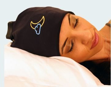 A person with closed eyes is lying on a white pillow, wearing a black cap with a yellow crescent moon and blue cloud design—possibly enjoying the benefits mentioned in many Sleep Shepherd reviews.