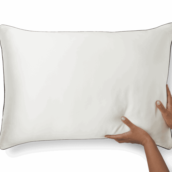 Two hands are shown adjusting or holding a white Silk Pillowcase against a black background. The pillowcase is rectangular and appears to be soft and plush.