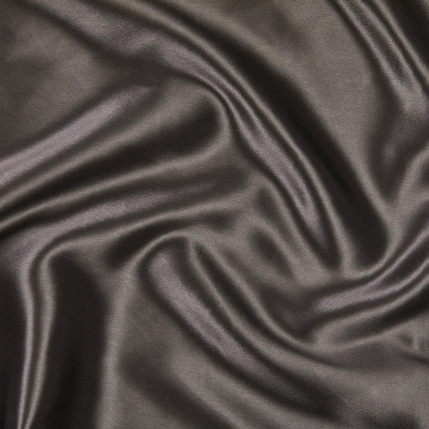 A close-up of the Silk Pillowcase, showcasing its smooth, dark-colored satin fabric with gentle folds and a soft sheen, highlighting its luxurious texture and elegant appearance.