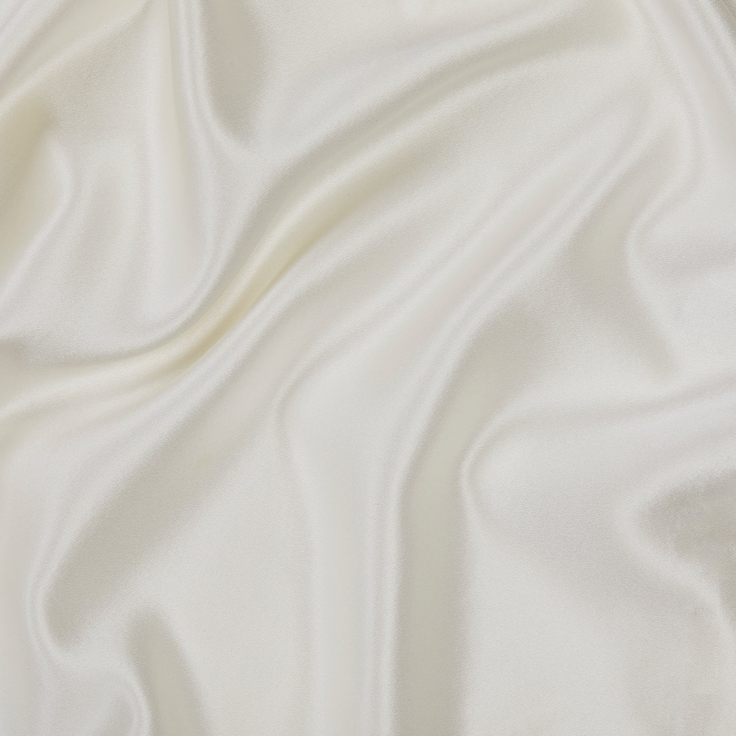 A close-up of the smooth, white fabric of our Silk Pillowcase, showcasing its soft, elegant folds and ripples that create a glossy and luxurious texture.