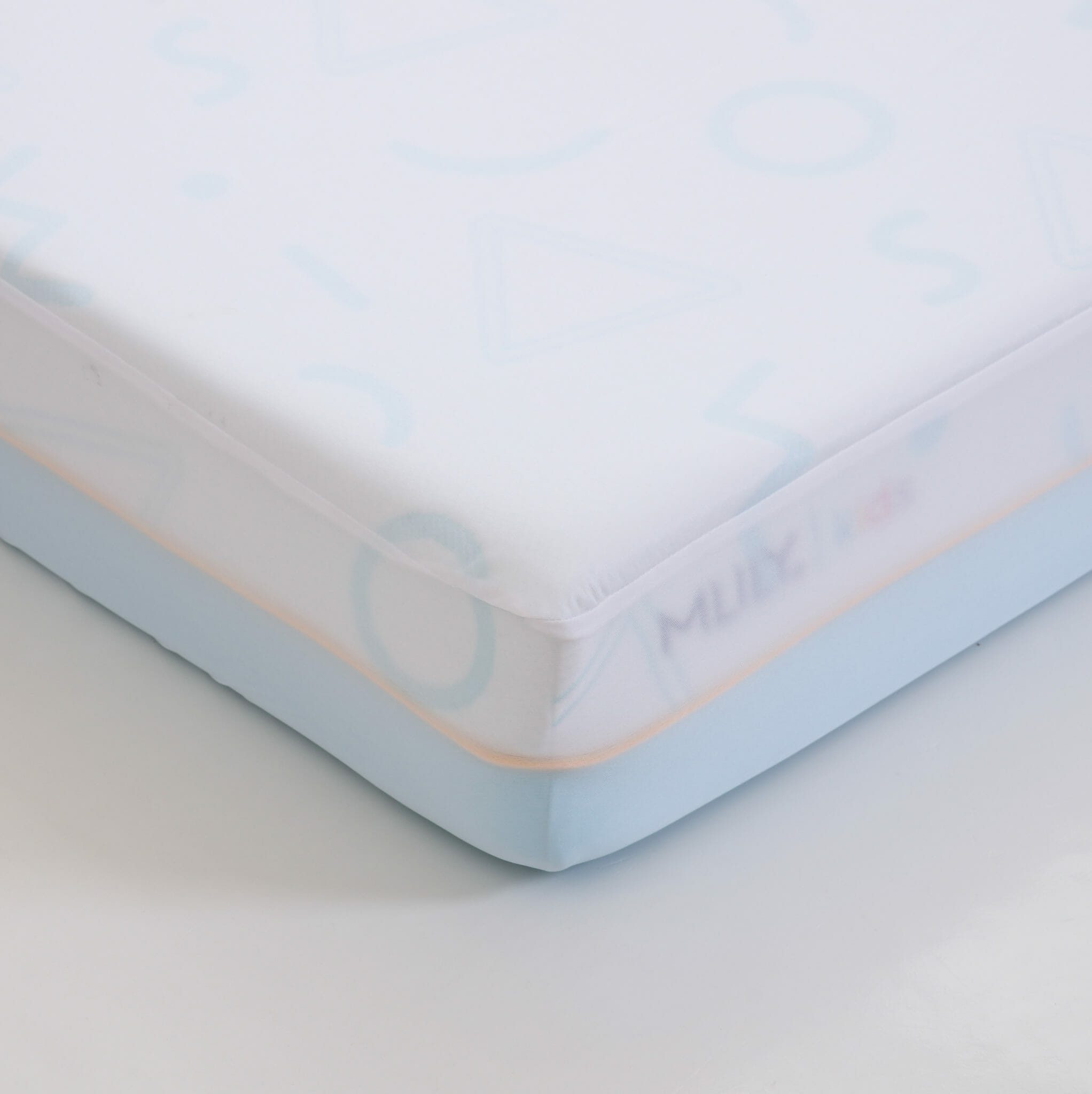 Image of a close-up corner of the Mlily JAMA 7" Mattress with a white and light blue cover featuring pastel shapes and letters. The mattress is placed on a white surface.