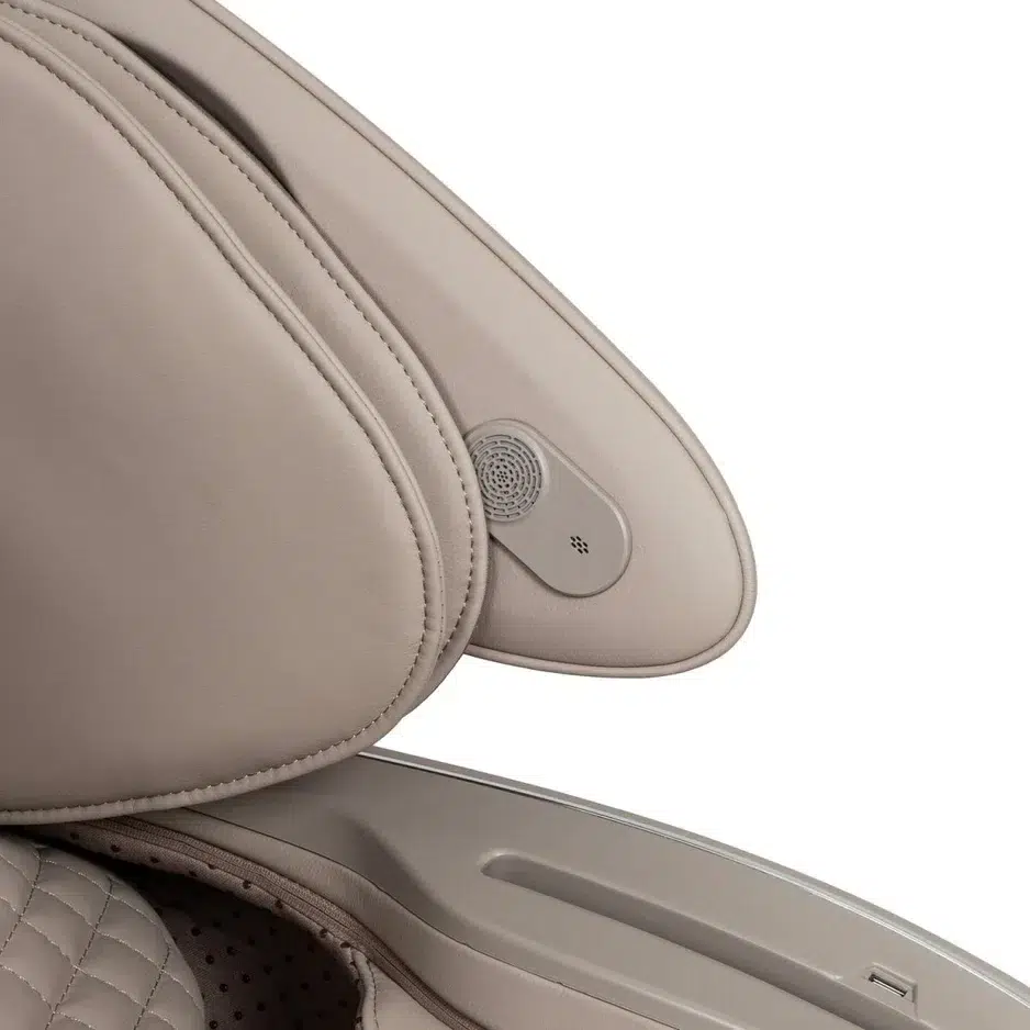 Close-up view of the Osaki Platinum Solis 4D+ headrest with an integrated speaker and control button. The quilted leather surface and sleek design suggest a premium vehicle interior.