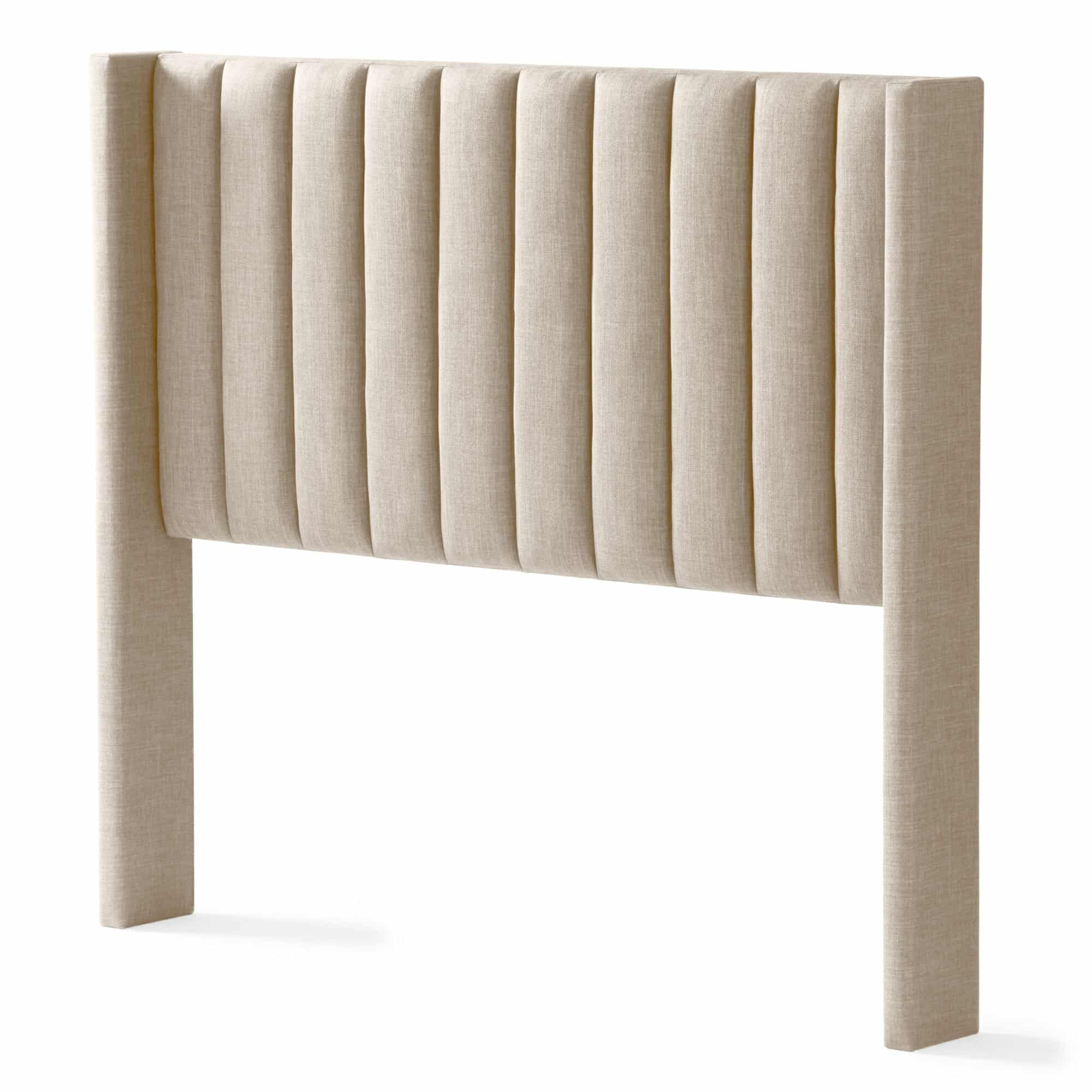 The Blackwell Headboard is a beige, upholstered piece featuring vertical tufted panels. It has a simple, modern design with a rectangular shape and extends to the floor with its two vertical legs. The fabric is soft with a linen-like texture.