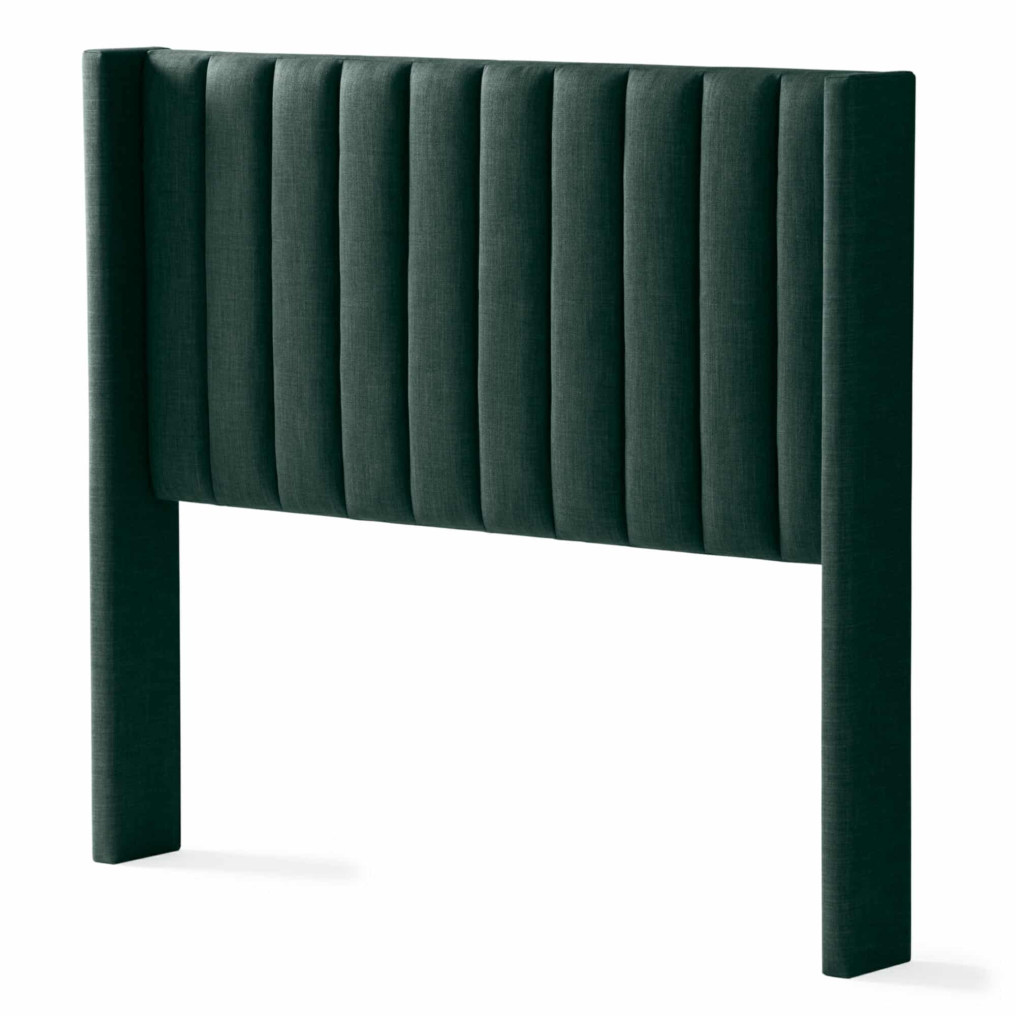 The Blackwell Headboard is upholstered in a dark green fabric with distinct, evenly spaced vertical panels. It extends to the floor with sturdy legs, showcasing a contemporary and minimalistic design.