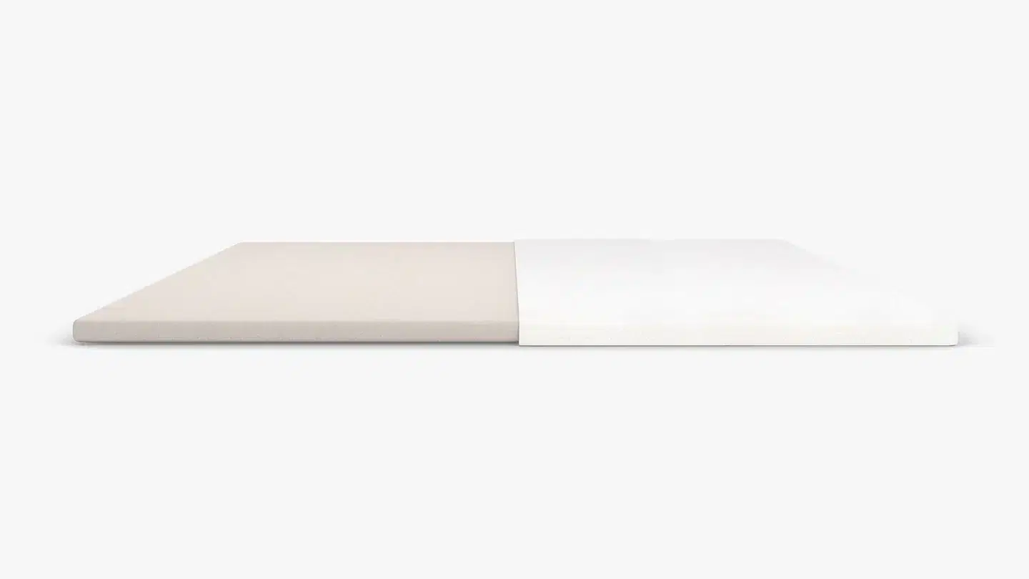 A minimalist image displaying a flat, rectangular Bear Pro Mattress Topper split evenly into two sections: the left half is a beige color, while the right half is white. The background is plain and light gray, emphasizing the two-tone color division.