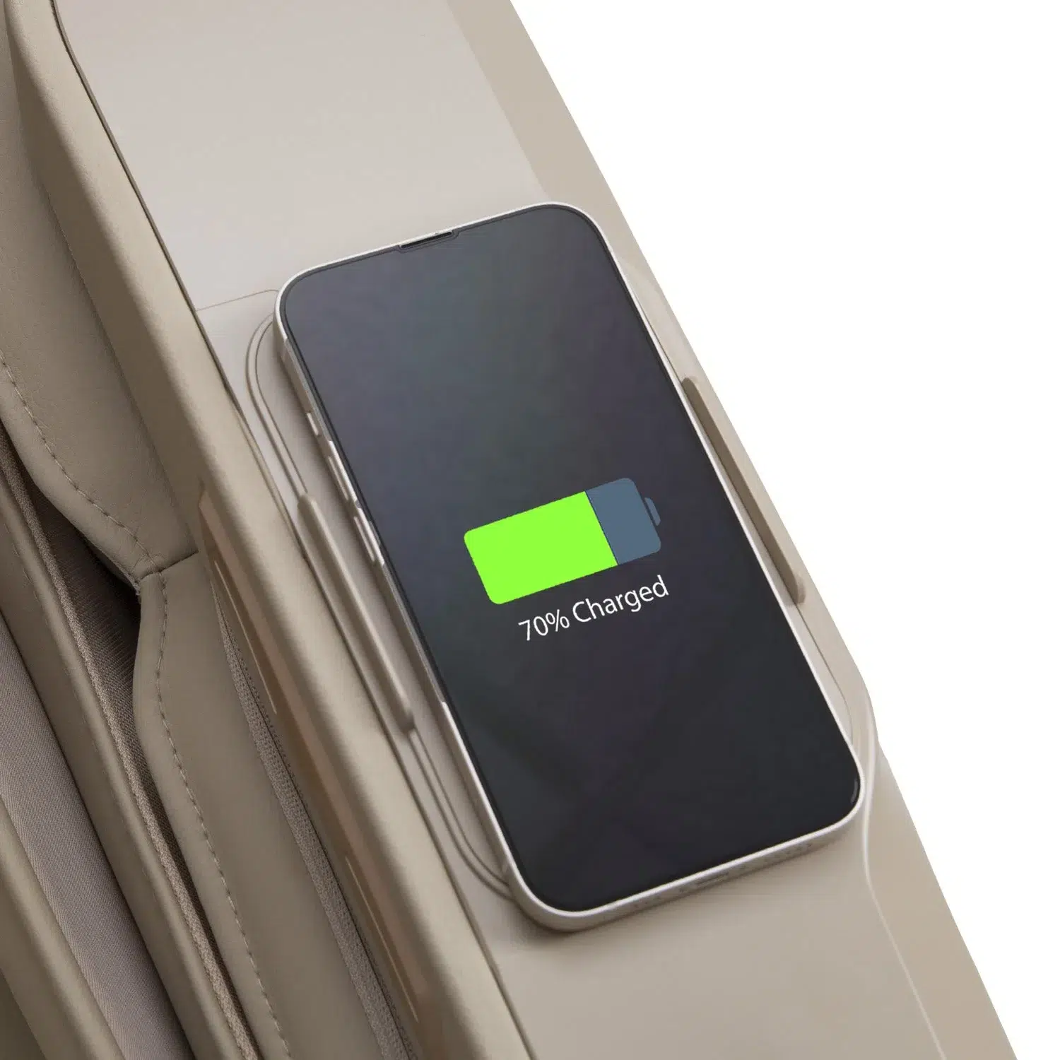 An Osaki 4D Maestro LE 2.0 is placed on the side of a beige suitcase, wirelessly charging and displaying "70% Charged." The suitcase features a groove designed to hold the smartphone securely during the charging process.