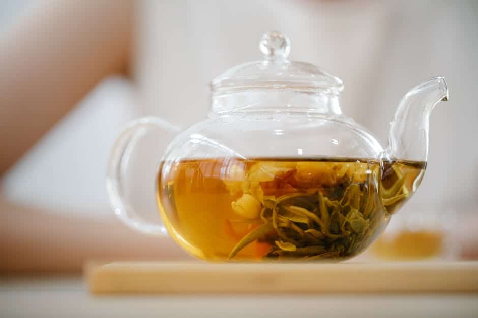 a glass teapot with a clear teacup filled with liquid