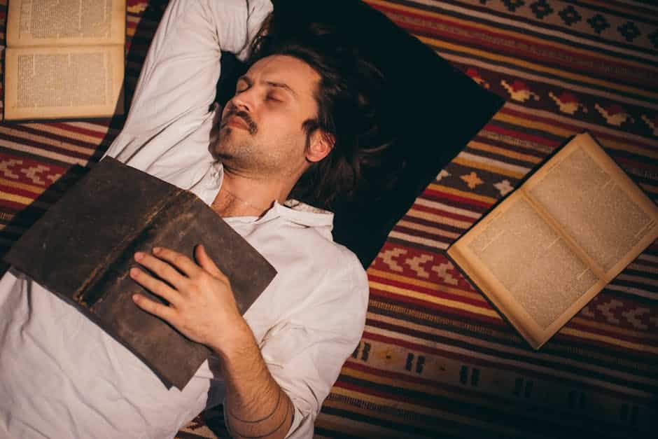 a man lying on a rug with a book