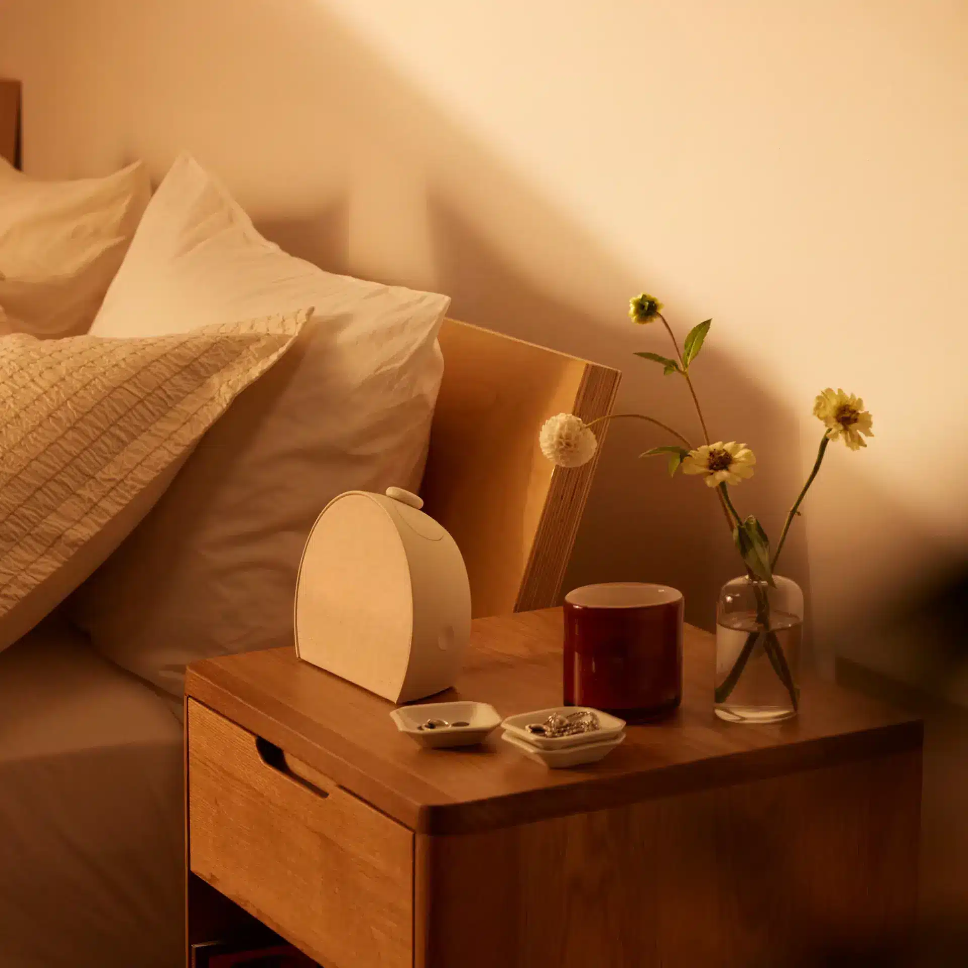 Hatch Restore smart alarm clock glowing on a bedside table