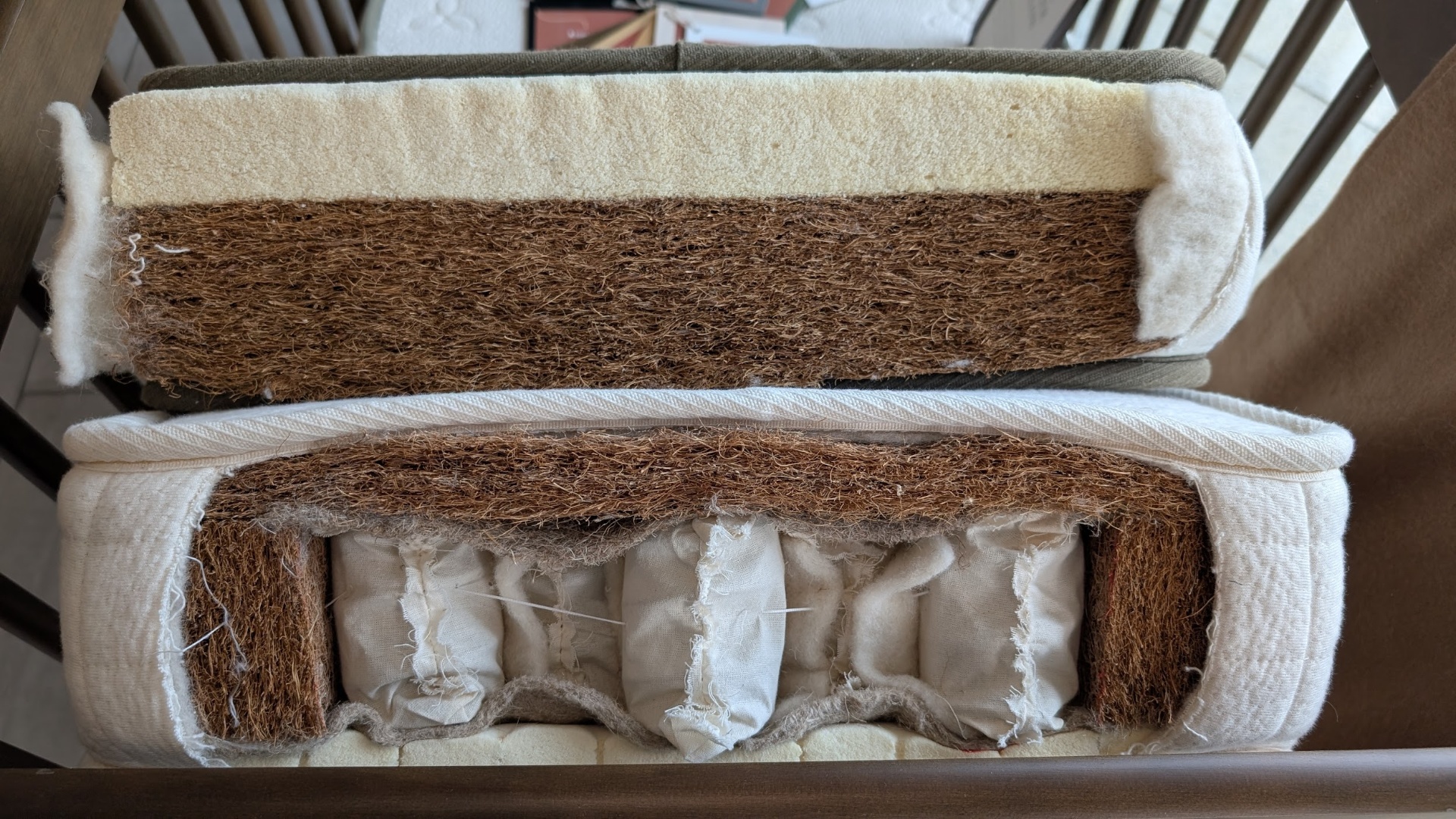 Cutaway view of two Avocado crib mattress models showing wool, coir, latex and pocketed coil layers