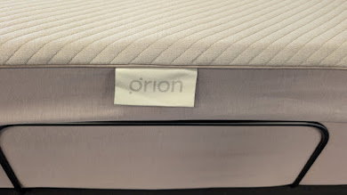Close-up of the Orion logo tag stitched on the side panel of the Orion Sleep smart cover